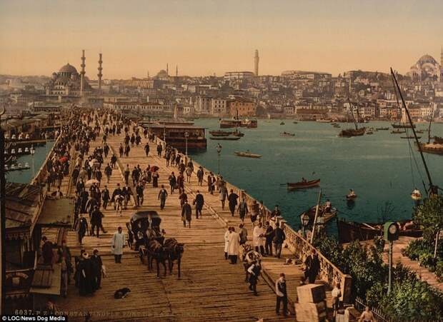 Сотни людей на мосту Галата и множество маленьких лодочек у берега Константинополь, османская империя, старые фотографии, фото в цвете, фотохром