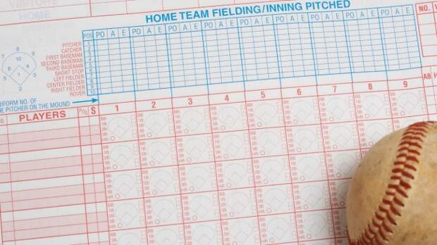 A baseball lays on a scorebook.