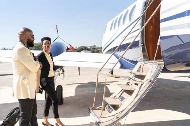 Two well-dressed people boarding a private plane on the tarmac.