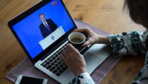 Девушка у себя в квартире в Новосибирске смотрит трансляцию ежегодного послания президента РФ Владимира Путина к Федеральному собранию. 1 марта 2018