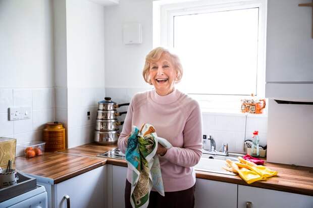 Smiling person drying hands on towel in kitchen.