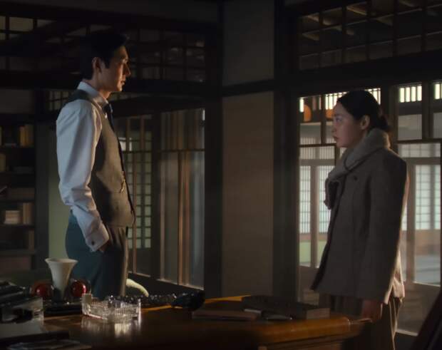 Vertical shot of Koh and Sunja facing each other in his 1945 home office