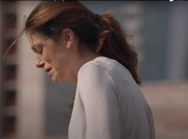 A distraught woman with a ponytail standing on the ledge of a tall building, preparing to jump off, on Law & Order: SVU Season 26 Episode 5