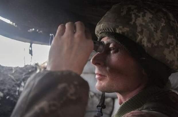 A service member of the Ukrainian armed forces uses binoculars while observing the area at fighting positions on the line of separation near the rebel-controlled city of Donetsk, Ukraine April 3, 2021. REUTERS/Serhiy Takhmazov