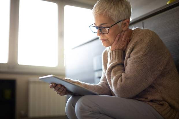 Person with a serious expression looking at a tablet.