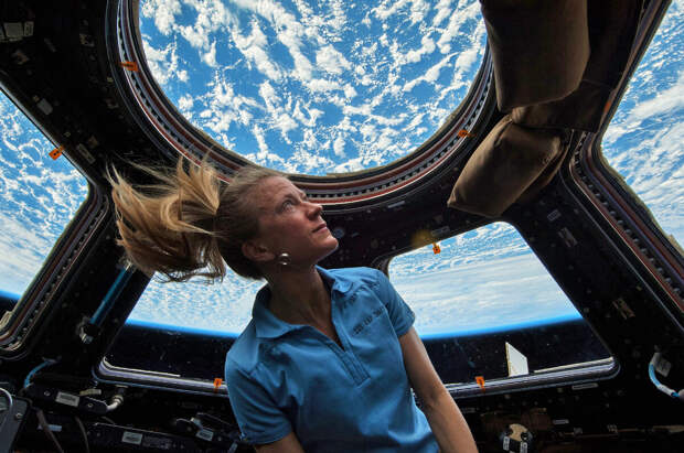 Фото: NASA / Астронавт Карен Найберг смотрит на Землю, находясь внутри модуля «Купол». Снимок сделан в 2013 году