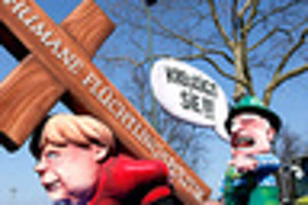 A carnival float with papier-mache caricatures mocking Bavarian Governor Horst Seehofer and German Chancellor Angela Merkel is displayed at a postponed "Rosenmontag" (Rose Monday) parade, at one location in Duesseldorf, Germany, March 13, 2016, after the original parade in February was cancelled due to severe weather. Words read 'crucify her' 'human politics for migrants'. REUTERS/Ina Fassbender