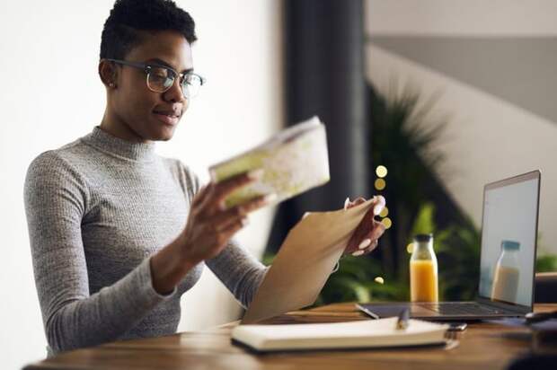 A woman at a desk with paperwork and a laptop.