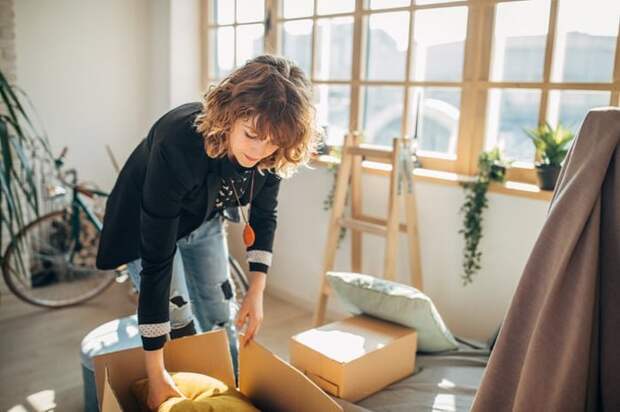 A woman packing moving boxes in a sunny apartment.