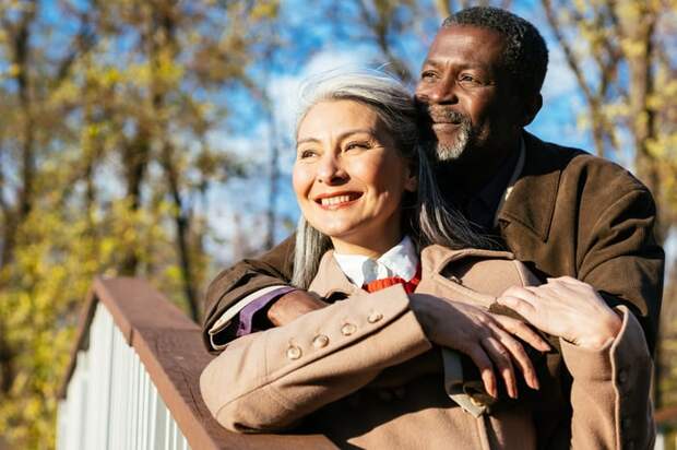Smiling couple standing on stairs looking off into the distance.
