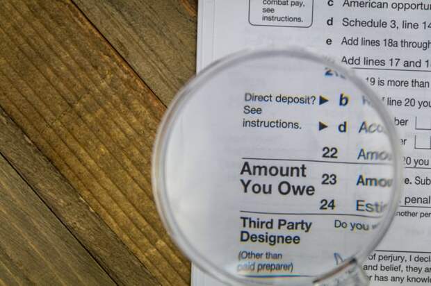 A magnifying glass held above an IRS tax form that's enlarging the phrase Amount You Owe.