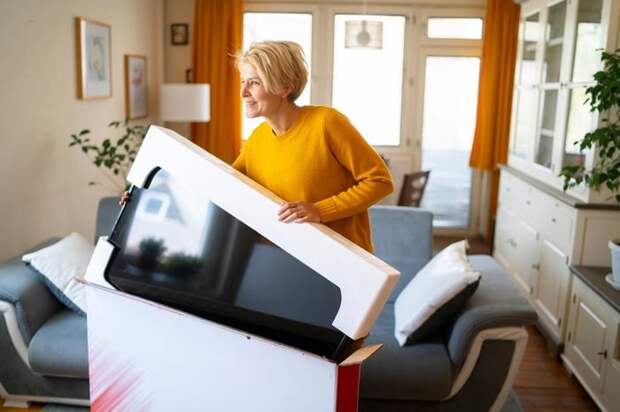 A person taking a new TV out of the box in their living room.