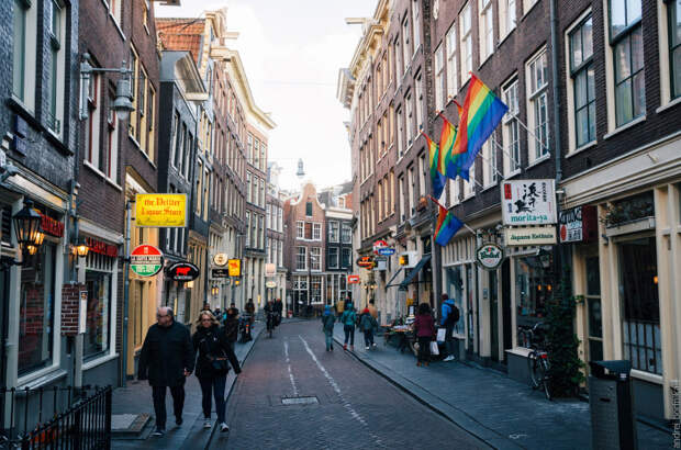 Tourist walking along a narrow street of the historical town part of Amsterdam.