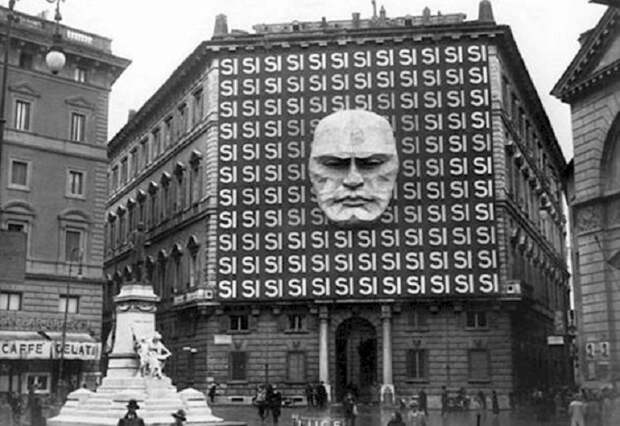 Огромное давящее здание украшено гигантским портретом Бенито Муссолини и многократно повторенным словом Si - «Да».