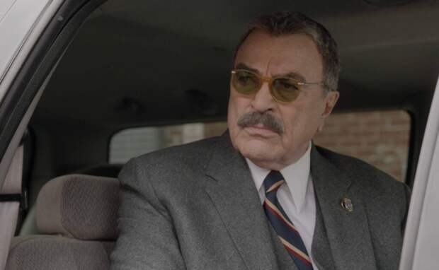 Frank sitting in the back of his government-driven car, looking serious with sunglasses on, on Blue Bloods Season 14 Episode 18