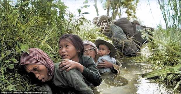 Местные женщины и дети прячутся в грязной канаве от интенсивного обстрела со стороны вьетконговцев в Бао Тай, примерно в 20 милях к западу от Сайгона Вьетнам, военное, война во вьетнаме, вьетнамская война, колоризация, колоризированные снимки, колоризированные фото, раскрашенные