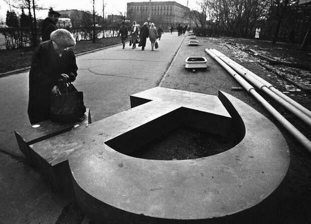 Женщина копается в сумке на поваленном серпе и молоте на улице в Москве, 1991 год   история, смотреть, фото