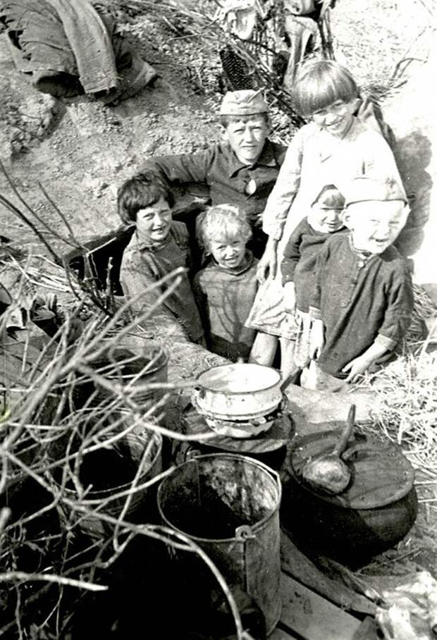 Дети колхозников одной из деревень Калининской области в лесу у землянки, где они жили в дни оккупации. 1942 г. Калининская область.
