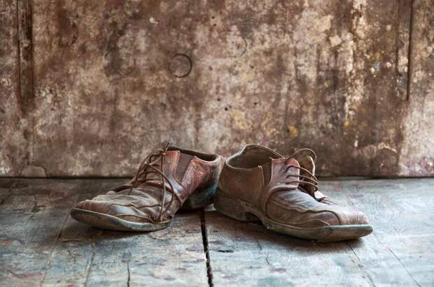 Old dirty brown leather shoes on wooden floor.