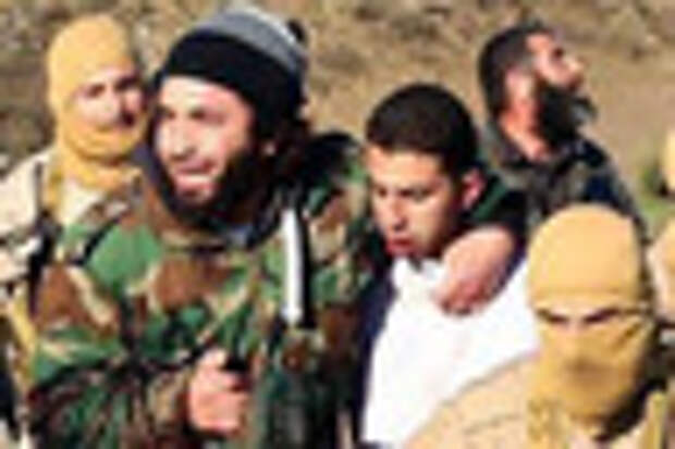 FILE - This Wednesday, Dec. 24, 2014 file image posted by the Raqqa Media Center, which monitors events in territory controlled by Islamic State militants with the permission of the extremist group, shows militants with a captured pilot, Mu'ath Al-Kaseasbeh, wearing a white shirt, in Raqqa, Syria. A video released online Tuesday, Feb. 3, 2015, purportedly shows a Jordanian pilot captured by the Islamic State extremist group in Syria last month being burned to death by his captors. The Associated Press was not immediately able to confirm the authenticity of the video, which was released on militant websites and bore the logo of the extremist group's al-Furqan media service