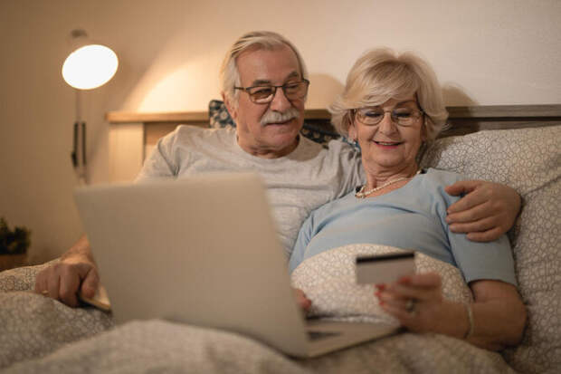 пожилая пара в постели с ноутбуком