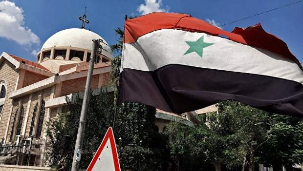 Государственный флаг Сирийской Арабской Республики у православной церкви в старом христианском квартале города Алеппо