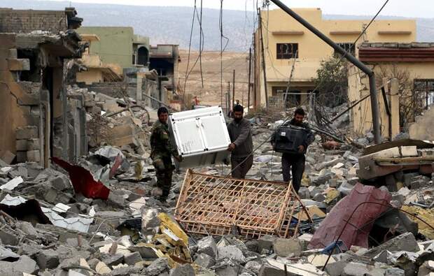 Volunteers from the Yazidi sect who have joined the Kurdish peshmerga forces with Yazidi people loot houses in the town of Sinjar