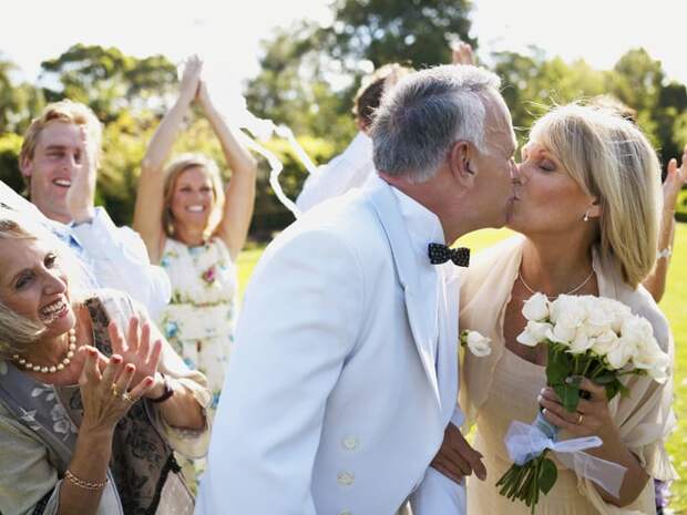 Newly married couple kissing as friends and relatives cheer.