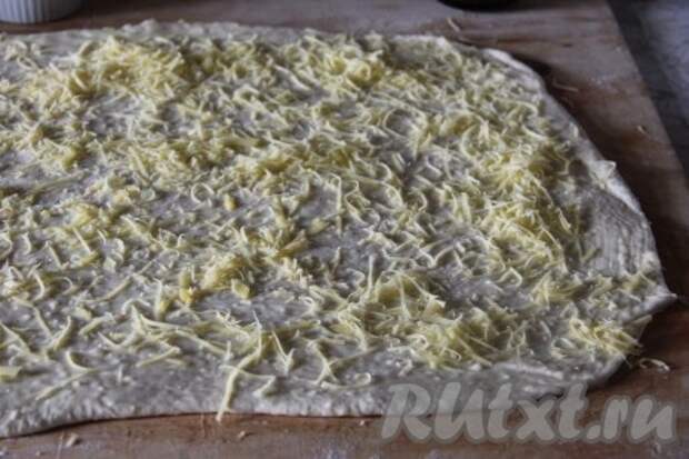 Готовое тесто раскатать в пласт, смазать его сливочным маслом комнатной температуры, распределить равномерно выдавленный чеснок. Сыр натереть на терке и присыпать наше тесто. 