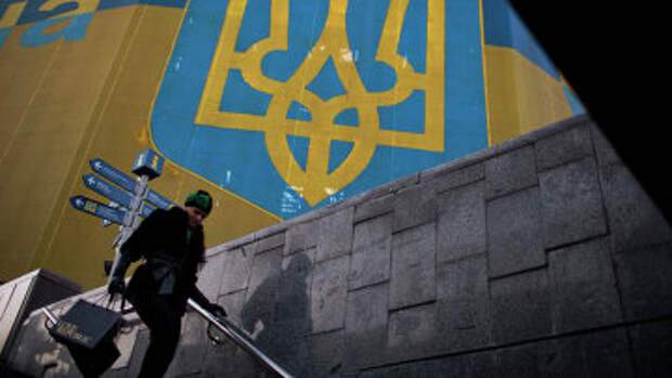 Женщина проходит мимо огромного украинского флага в центре Киева