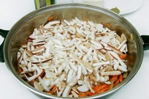 Высыпаем грибы на сковороду к обжаренным луку и моркови. Обжариваем их немного под крышкой.