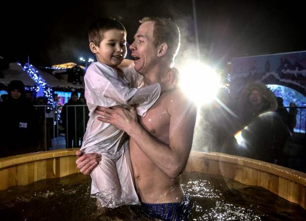 Папа с ребенком во время крещенских купаний в купели на Площади Революции