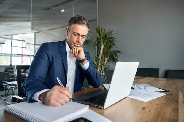 A professionally dressed person at a table taking notes.
