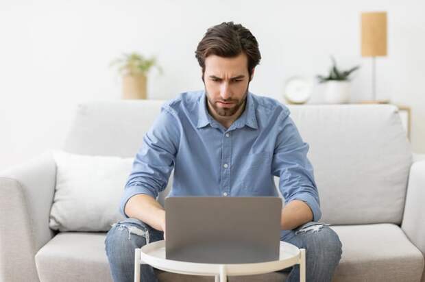 A person seated on a couch using a laptop.