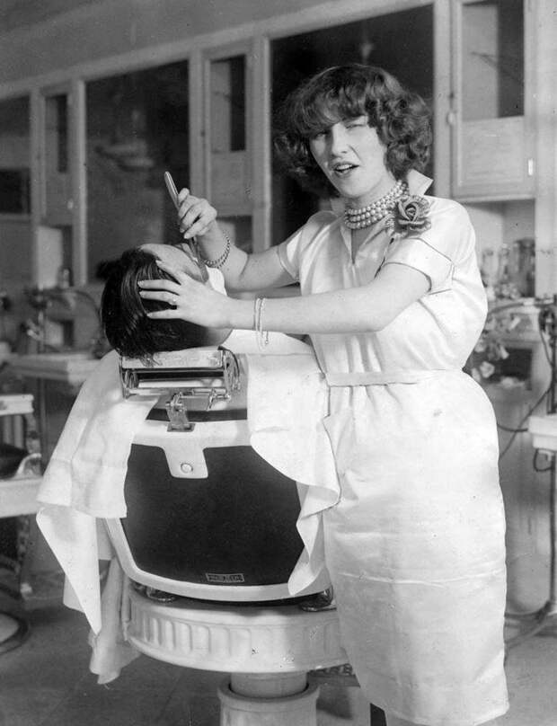 Первая лицензированная женщина парикмахер Нью-Йорка мисс Джин Деверо позирует фотографу во время бритья клиента, 1927 год  история, люди, фото