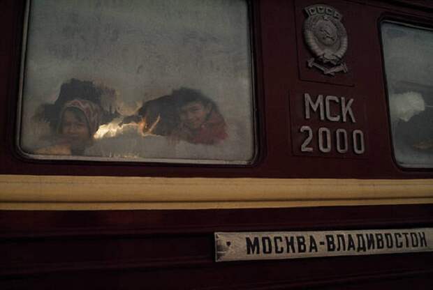 Дети выглядывают из вагона на станции Транссибирской магистрали.