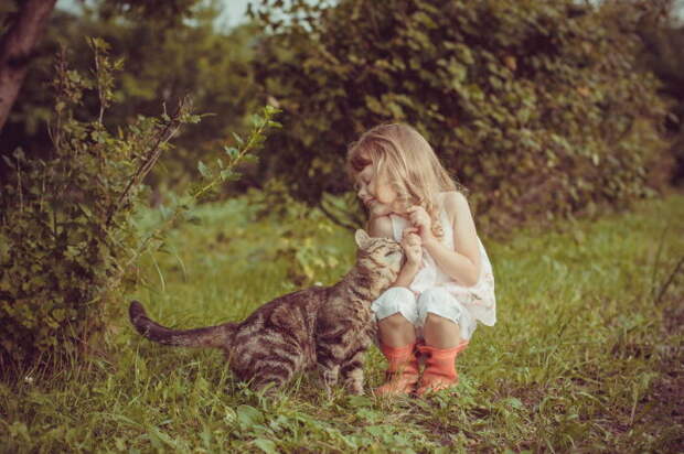 Маленькая девочка играет на полянке со своим усатым другом.