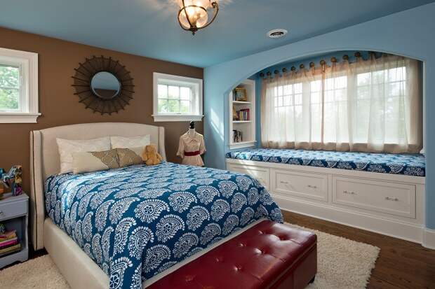 Интересное оформление комнаты в синих тонах с window seat, который украшает общую картину комнаты.