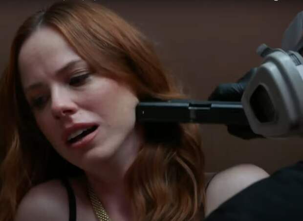 Redhaired woman with a gun pressed into the side of her neck on Law & Order: SVU Season 26 Episode 3