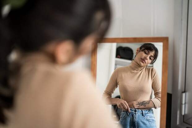 Person trying on clothing in mirror.