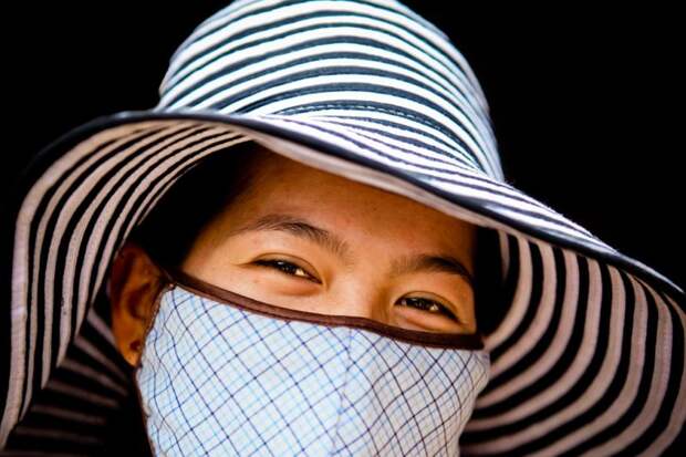 Женщина в маске улыбается во Вьетнаме