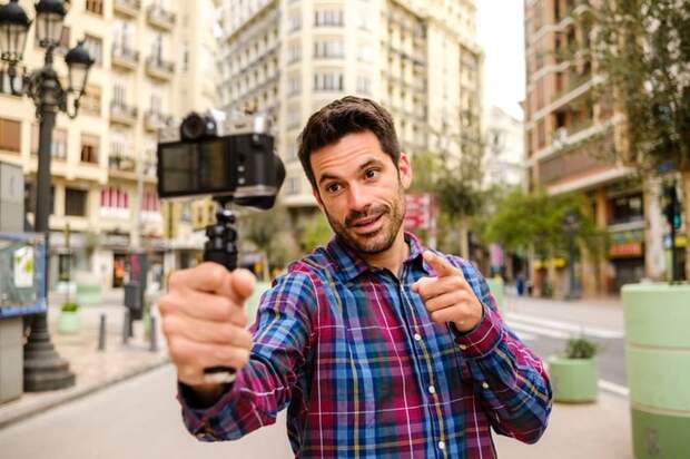 Person outdoors recording a video of himself on camera.