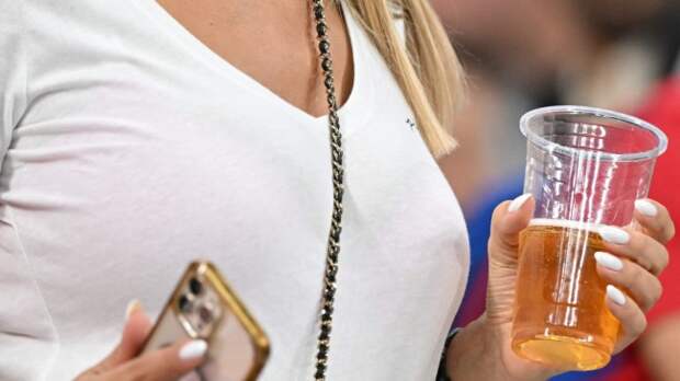 A female fan holds a beer at a sporting event.