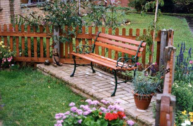 Стильная деревянная скамейка на небольшом садовом участке. 