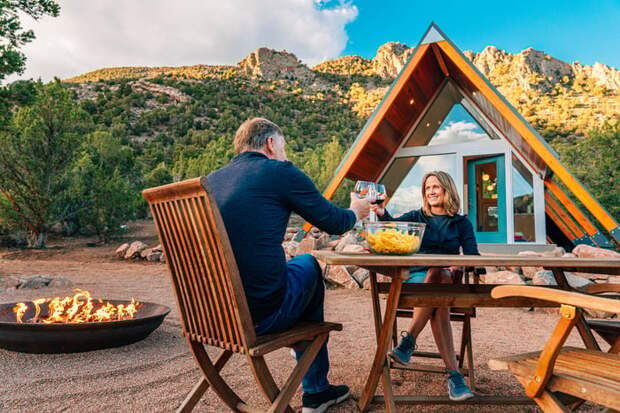 Couple toasting over table outside home.
